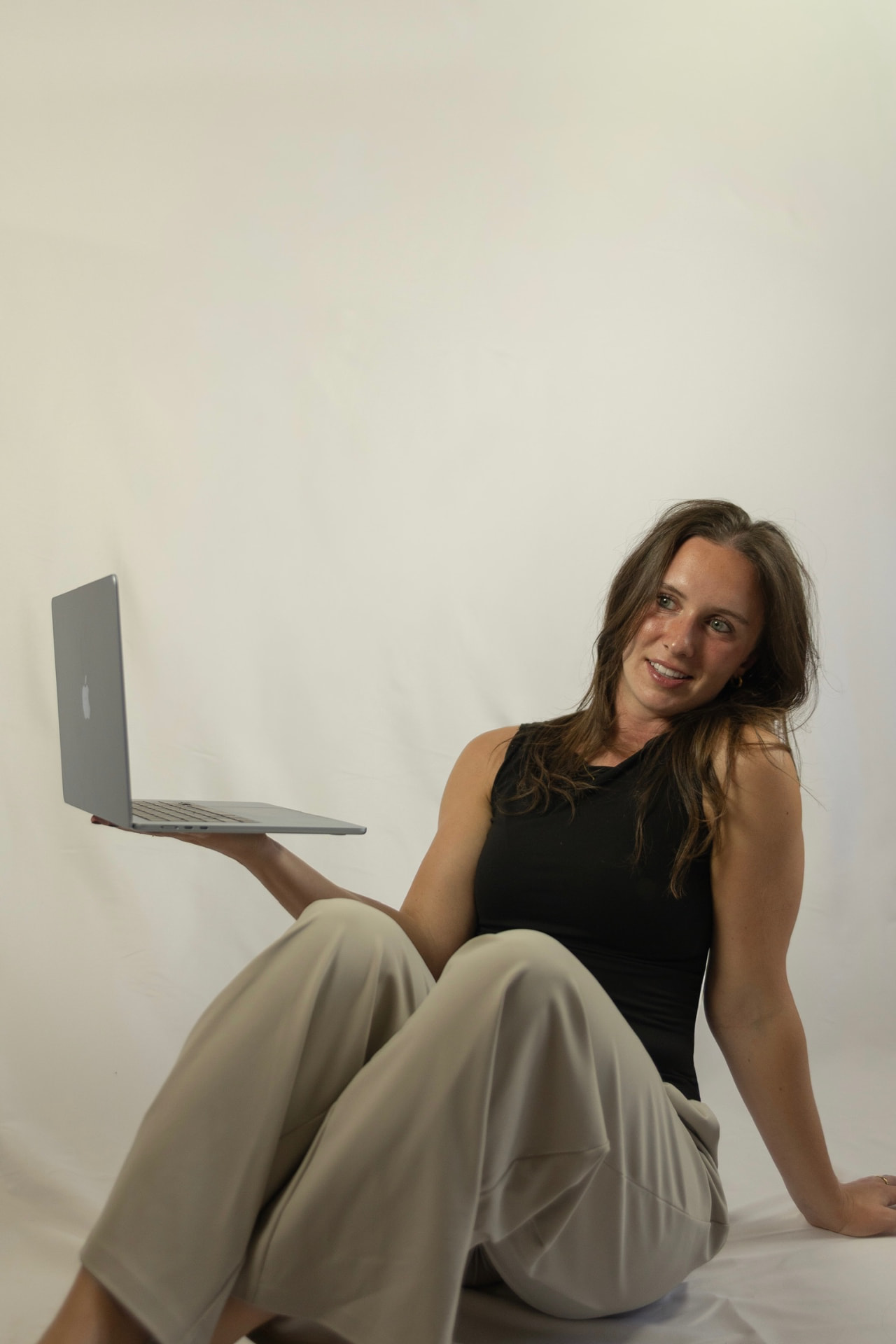 Laetitia Asper seated on the floor balancing a laptop on her hand