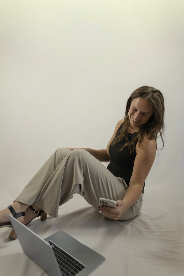 Laetitia Asper seated on the floor with a phone and laptop